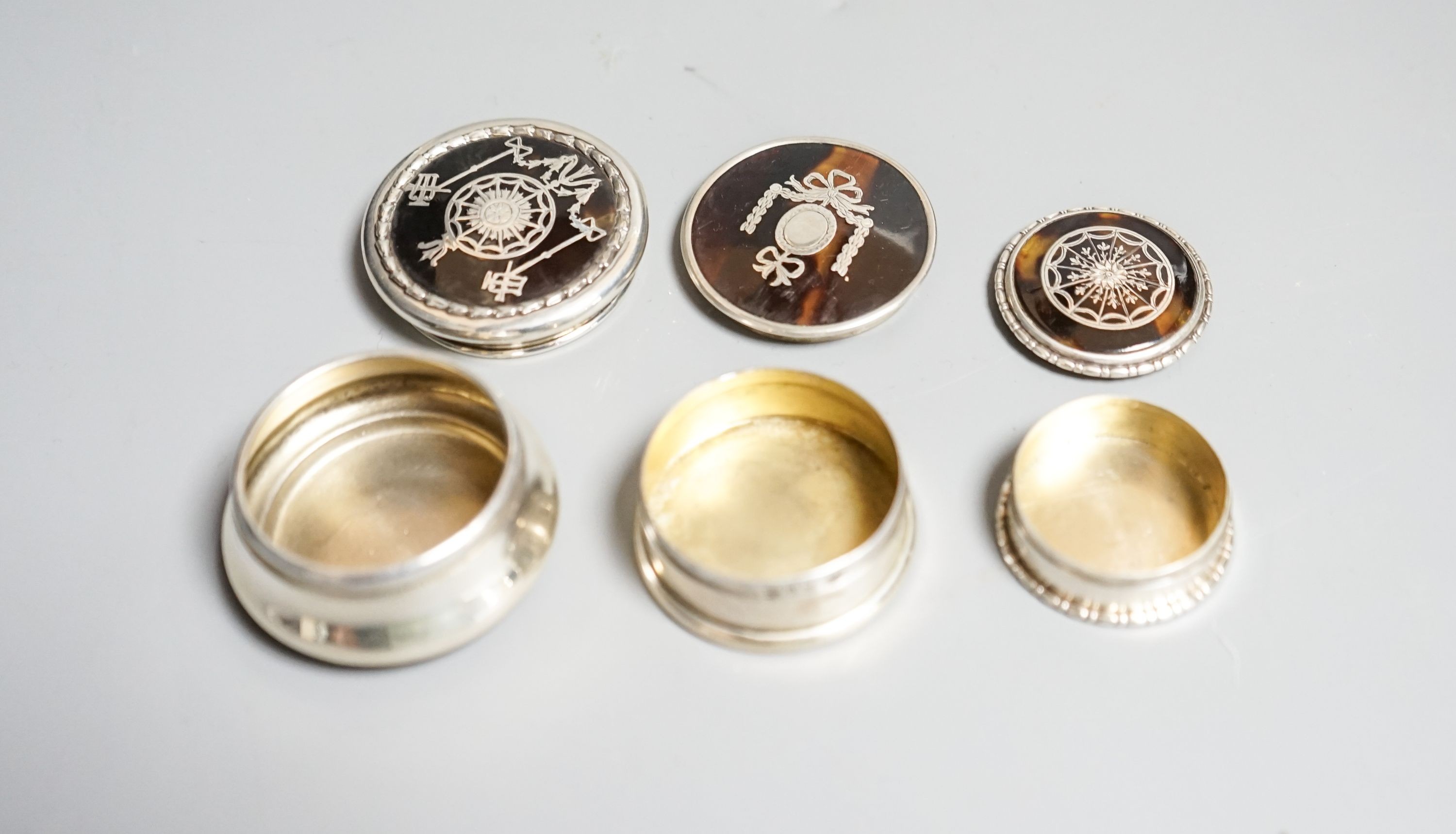 Three assorted early 20th century small silver and tortoiseshell pique circular boxes and covers, largest by William Comyns, 46mm.